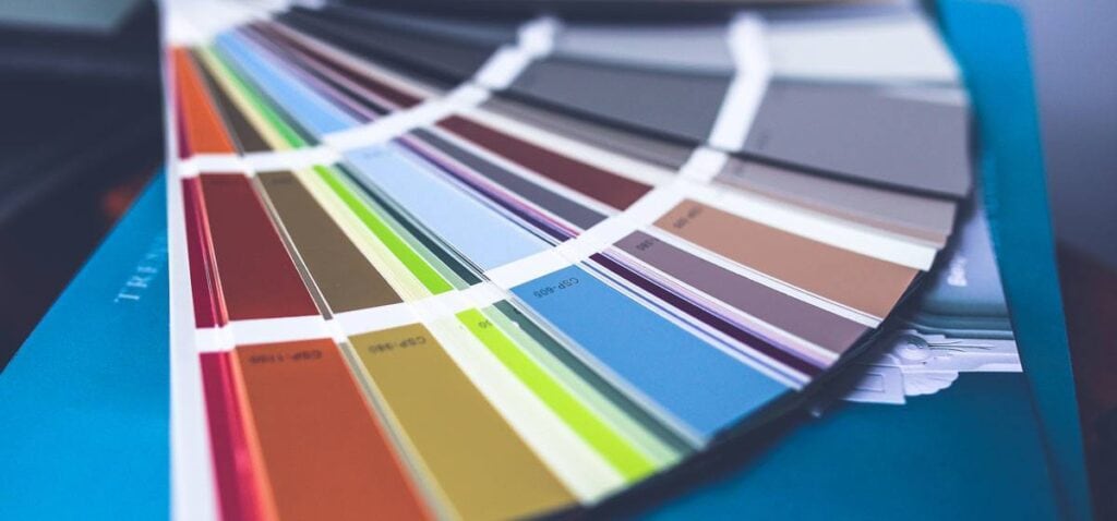 A close-up of a fanned-out color swatch book, displaying a wide range of paint color samples on rectangular cards arranged in an arc.