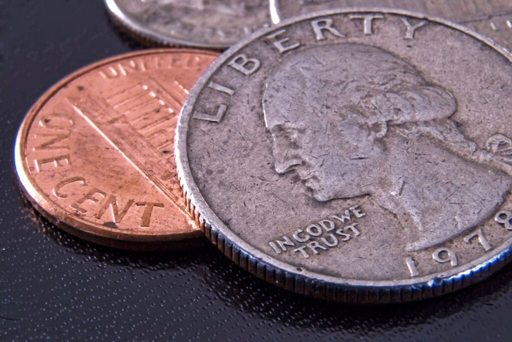 A close-up of a 1978 U.S. quarter partially overlapping a U.S. penny, both resting on a dark textured surface.