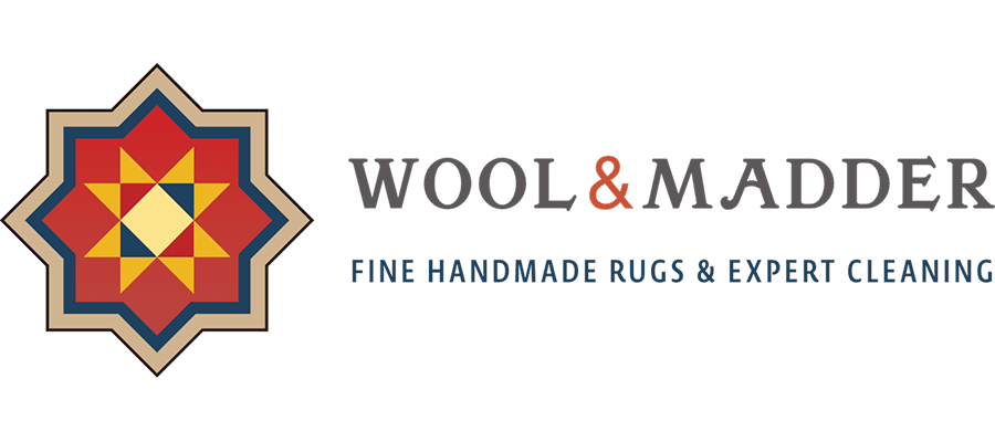 Star-shaped geometric rug pattern on the left; to the right, “WOOL & MADDER” is written in large letters, and below, in blue text, “FINE HANDMADE RUGS & EXPERT CLEANING.”.